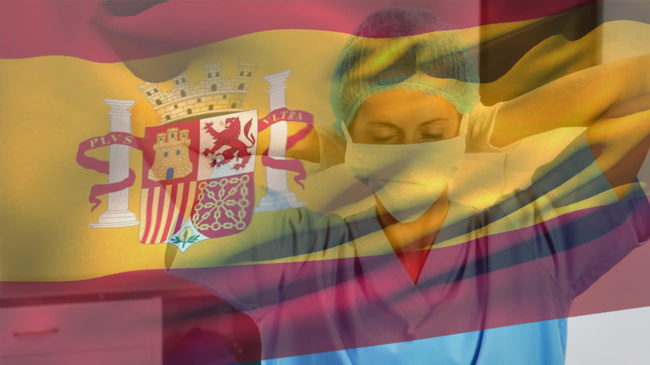 bandera española ondeando contra la trabajadora de salud caucásica que lleva una máscara facial en el hospital