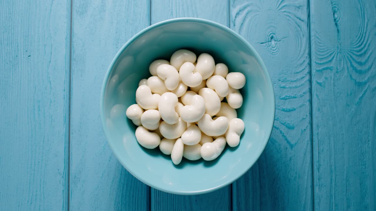 TOP VIEW: Male hand taking a lot of white chocolate candy from a bowl.