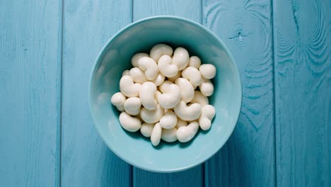 top view: male hand taking a lot of white chocolate candy from a bowl.