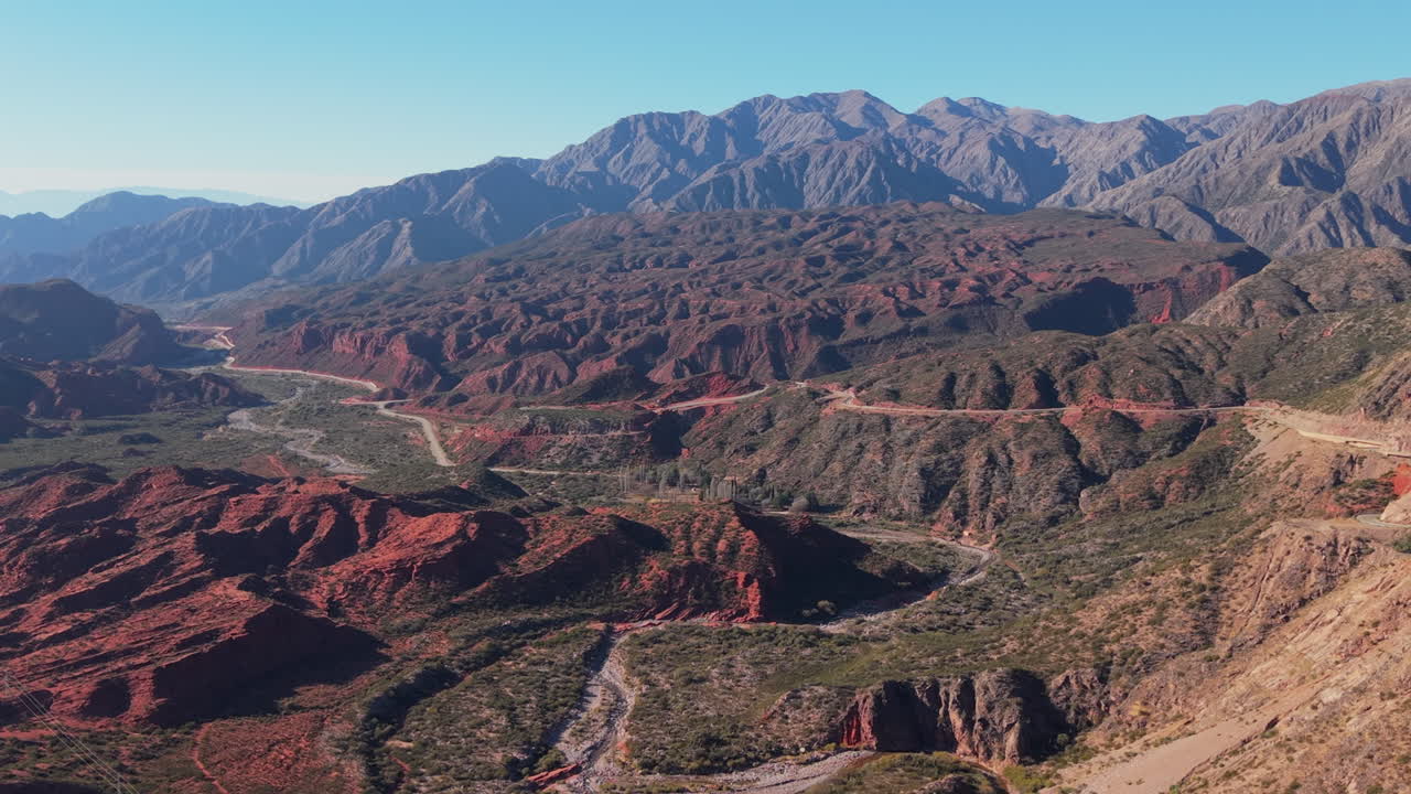 Cuesta de Miranda's layered red rock formations and distant peaky mountain ridge from above, Chilecito, La Rioja Province, Argentina