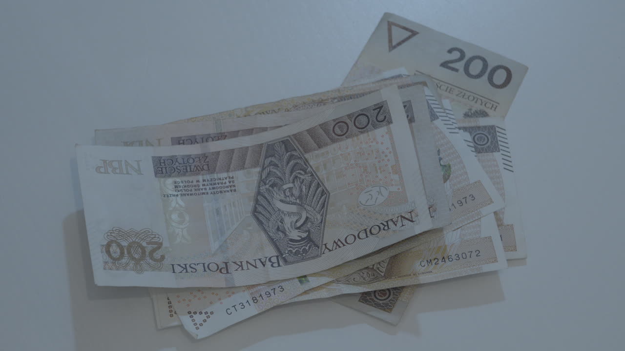 Man's Hand stacking polish zloty banknotes on a table