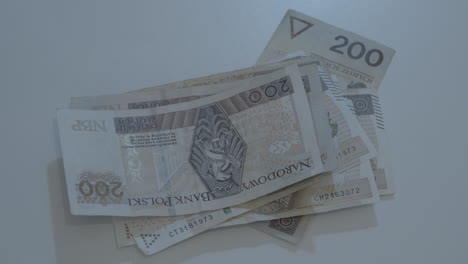 die hand eines mannes stapelt polnische zloty-banknoten auf einem tisch