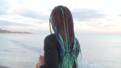 back of woman with braids running on the beach