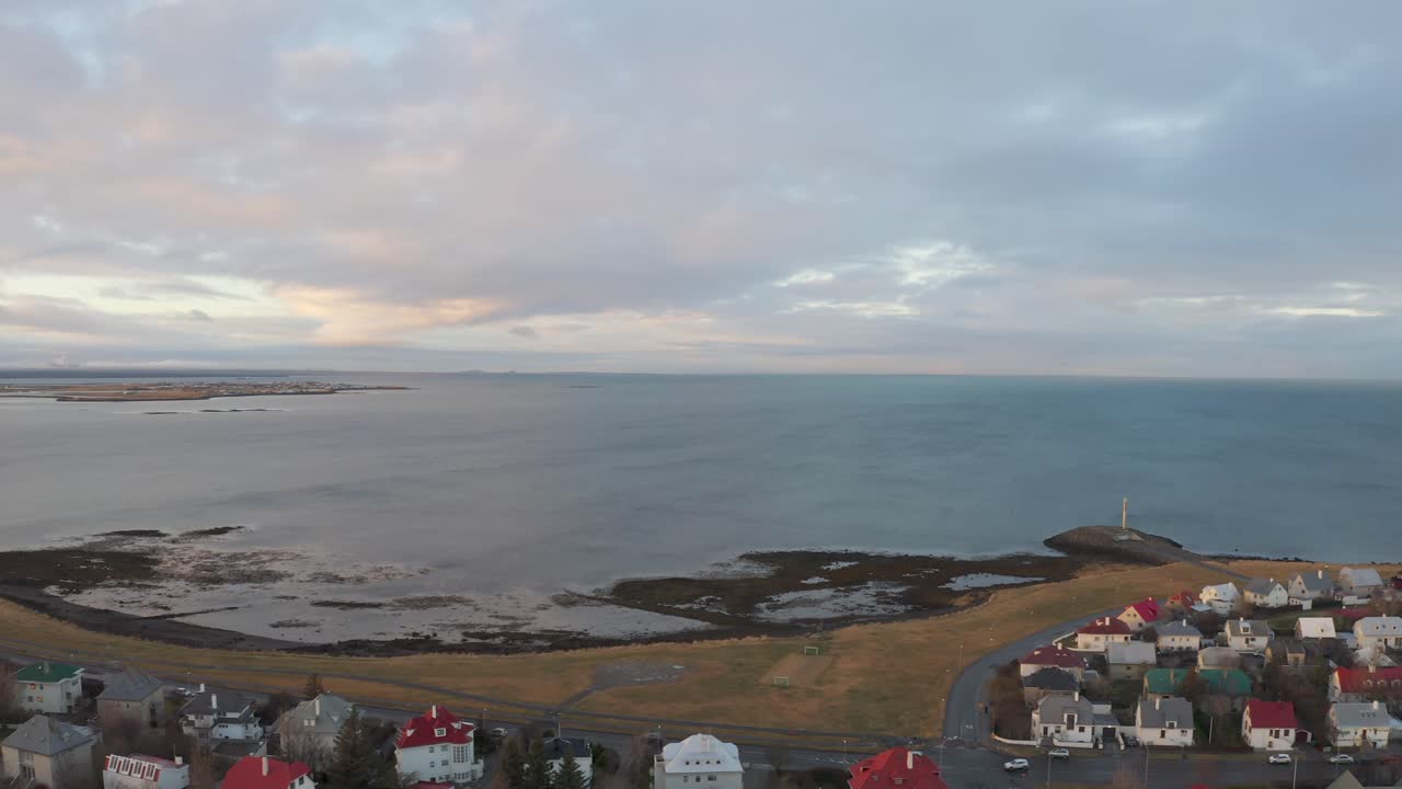 Looking out from Over Residential Rooftop Houses in Reykjavik showing the Amazing Icelandic Ocean during Sunset, Drone Aerial