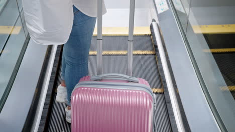 woman with pink suitcase on escalator