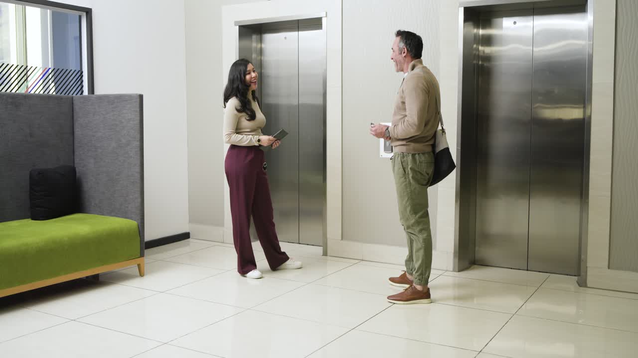 Colegas de trabalho diversos se cumprimentando após as portas do elevador deslizarem e se abrirem, trocando dispositivos que atualizam o trabalho