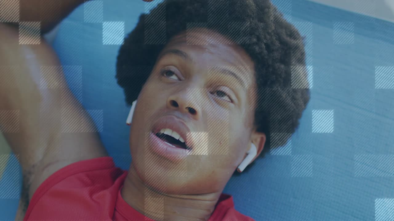 Man lying on blue mat, raising arm and wiping eyes post-workout, grid overlay tracking breathing
