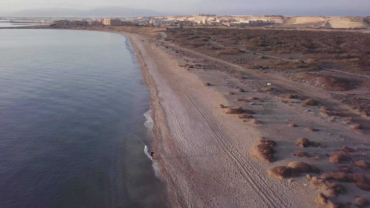 Man running on the beach. Orbital shot with drone