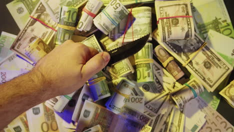 hand holding a knife over money