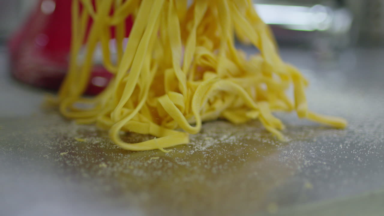 Close up of fresh pasta being cutted with a professional pasta cutting machine, fettucine.