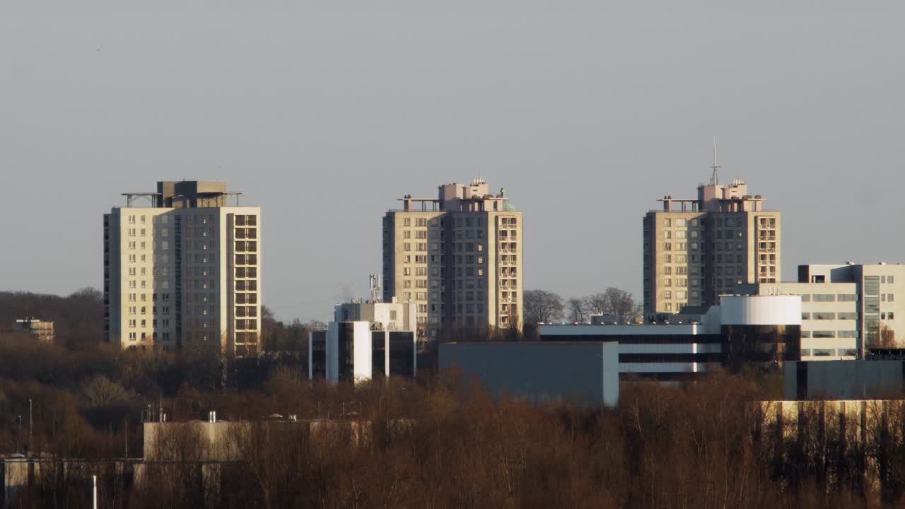 Close-up of three identical social housing towers in Kiel, Antwerp, illuminated by warm evening light