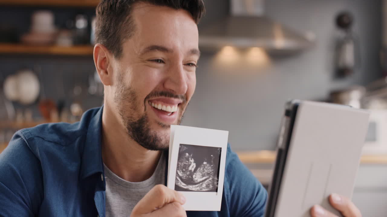 Happy man sharing his ultrasound while talking to friends over internet using digital tablet app video