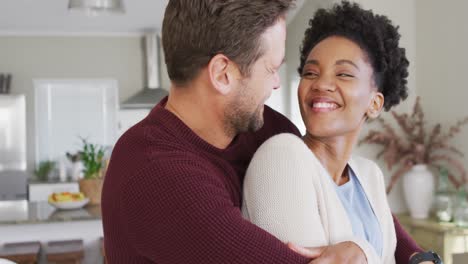 Video-of-happy-diverse-couple-hugging-in-kitchen