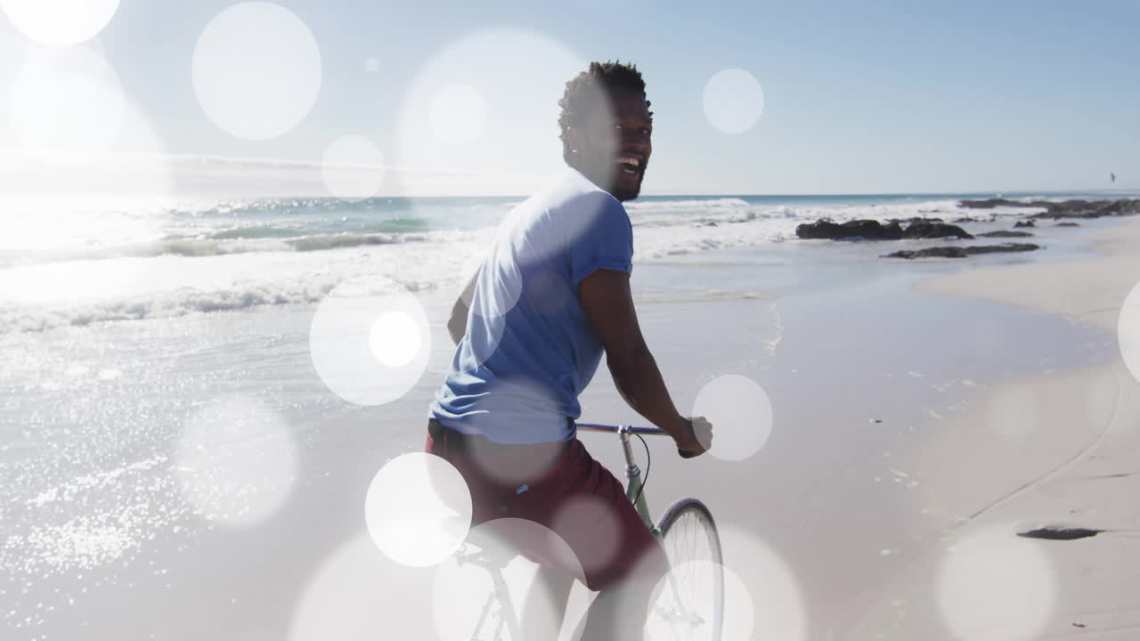 Riding bicycle on beach, man with bright animation bokeh light effects