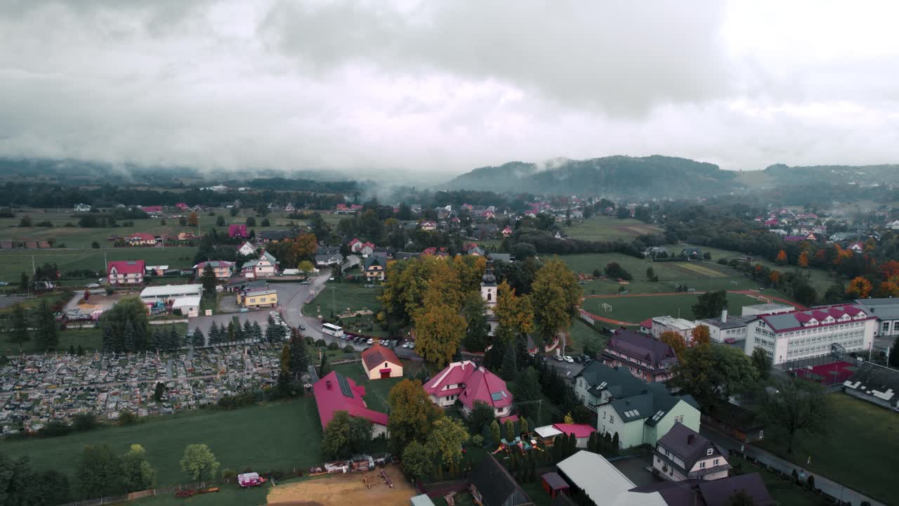 Images aériennes d'un paysage de campagne brumeux, de nuages, de maisons et d'une église blanche un jour d'automne