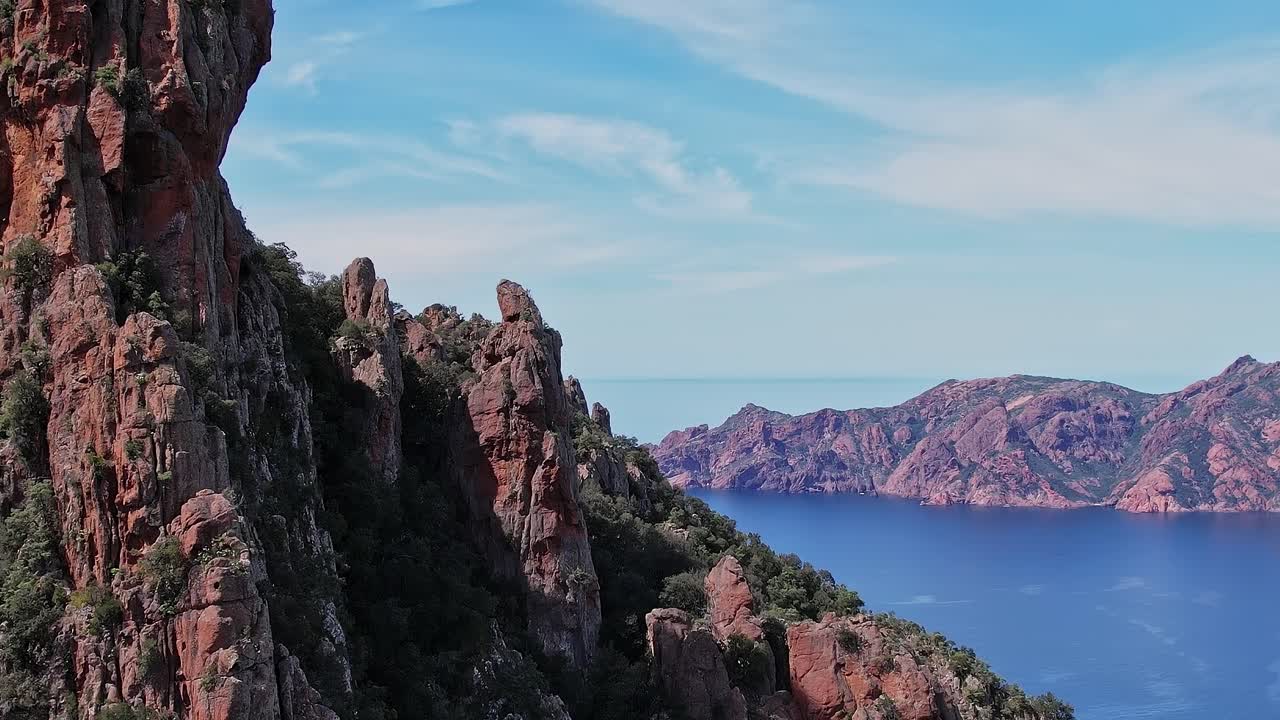 Le montagne si ergono sull'acqua in Corsica, Francia, durante il giorno