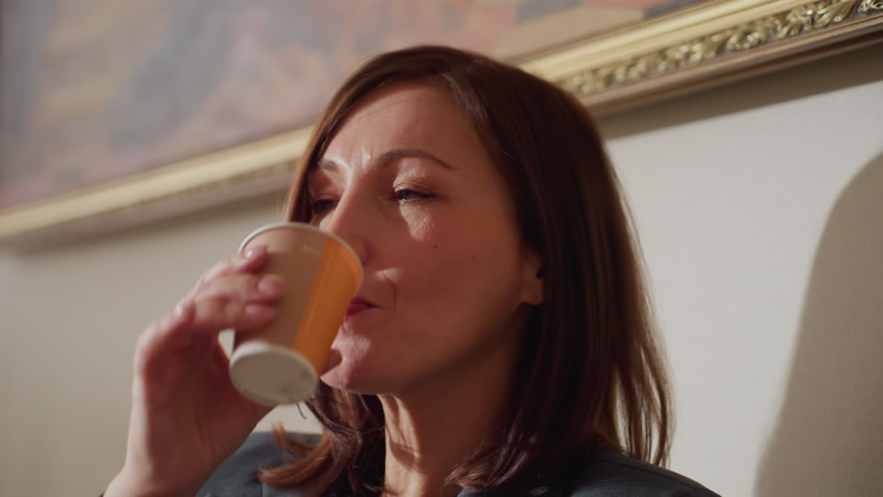 Close-up of businesswoman enjoying hot beverage with eyes closed, savoring peaceful moment during break, warm lighting on relaxed expression, capturing sense of comfort, mindfulness, and satisfaction