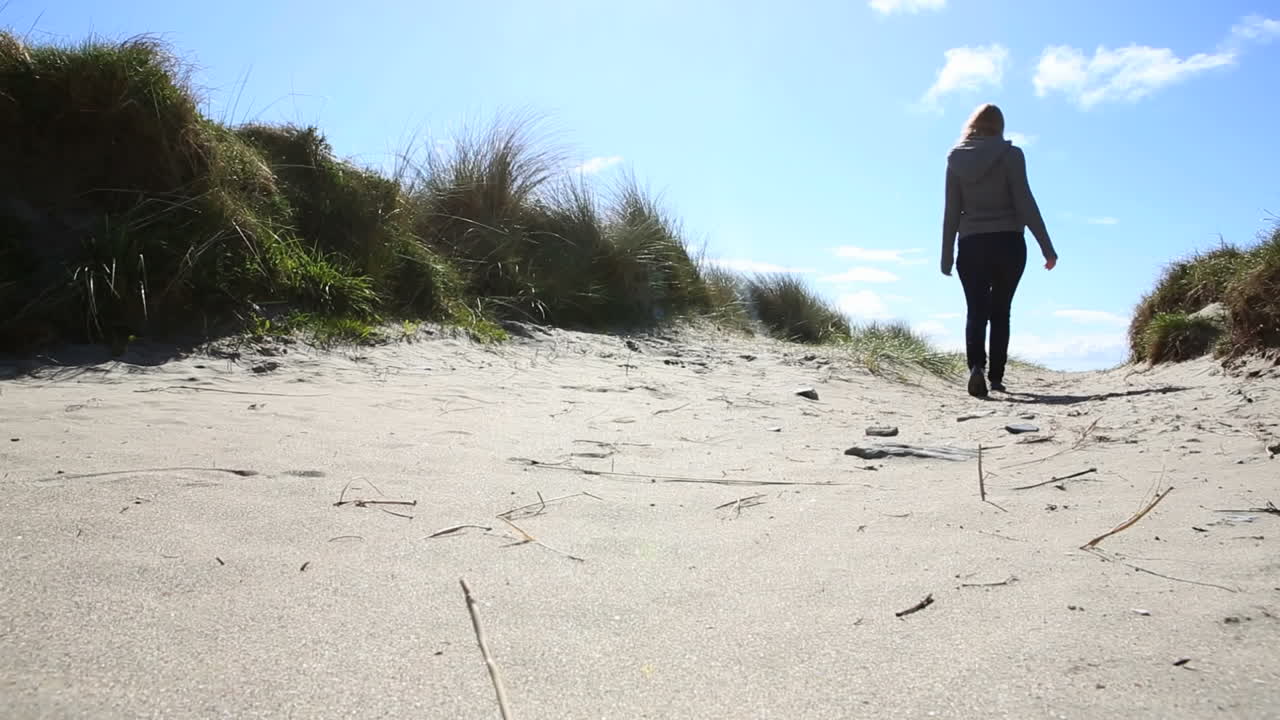 una mujer rubia caminando por la playa.