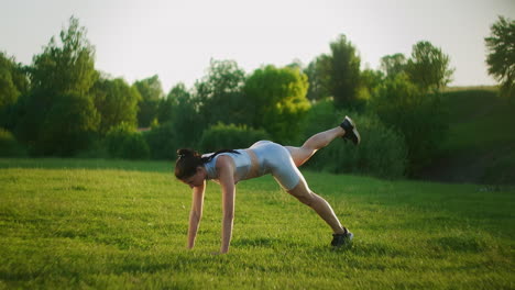 woman athlete involved in fitness in park doing leg lifts on mat. workout. work on a beautiful body in the morning or at sunset. exercises for leg and hip muscles