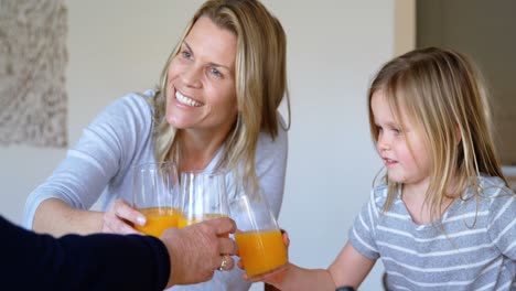 multi-generation family having orange juice at home 4k