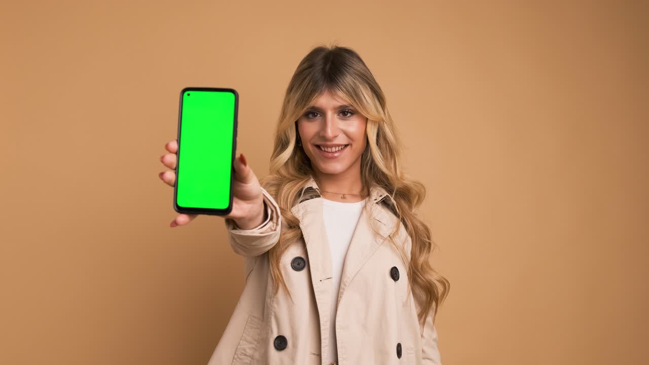 Happy transgender woman showing smartphone with blank green screen