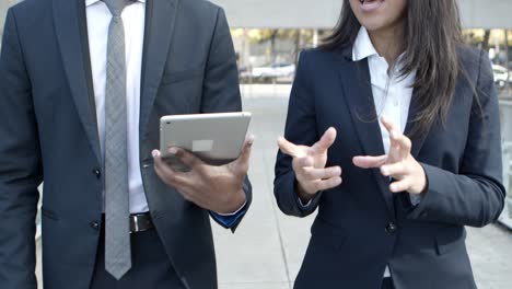 Coworkers-with-tablet-pc-walking-on-street