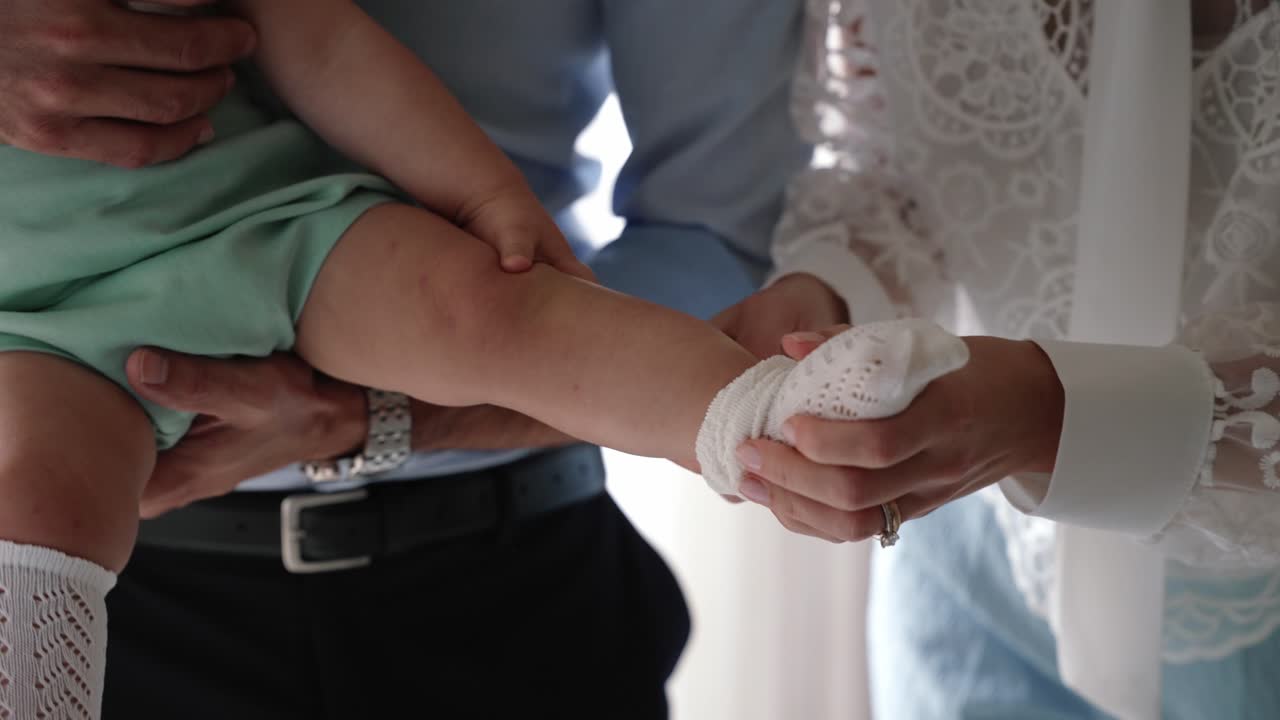 Parents gently putting lace socks on baby's feet with love and care