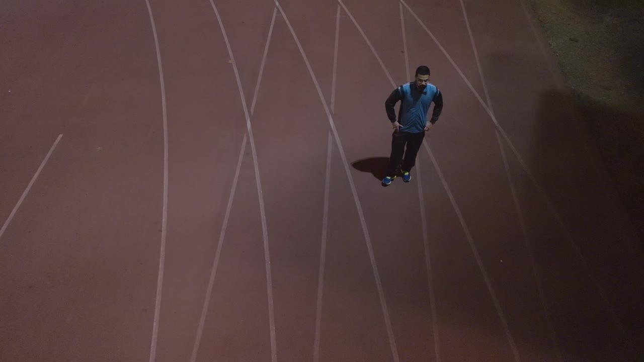 운동을 계속하기 전에 신선한 공기를 마시며 트랙에서 쉬고 있는 청년