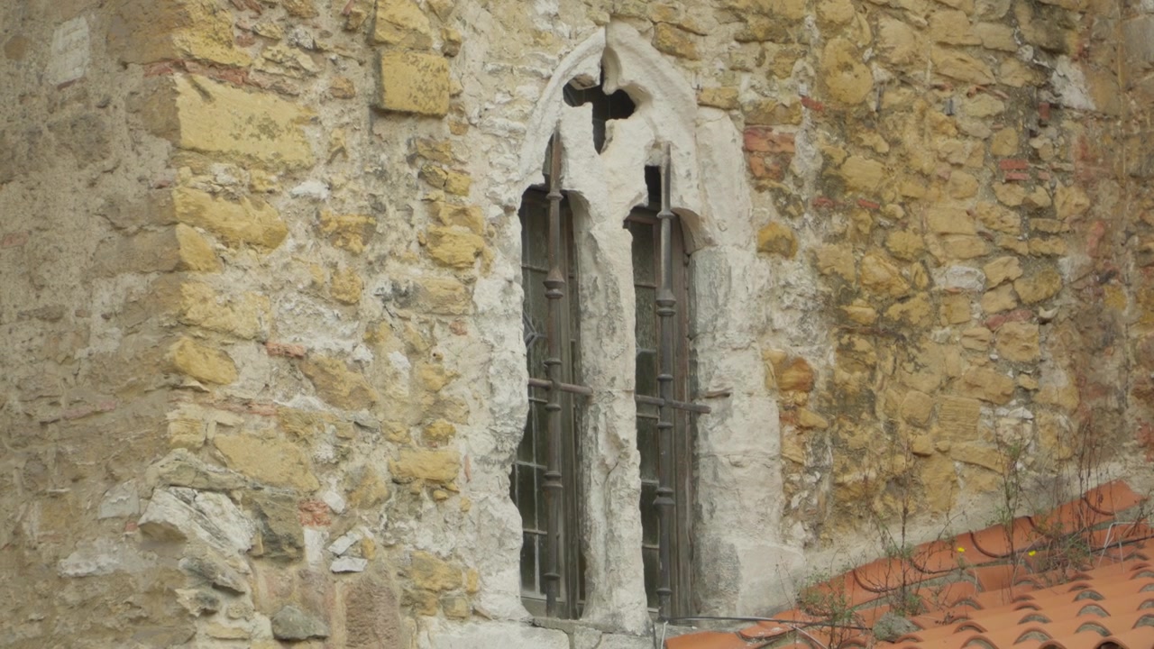 Dettaglio esterno di una finestra gotica a bifora sulla facciata in pietra di una storica cattedrale spagnola