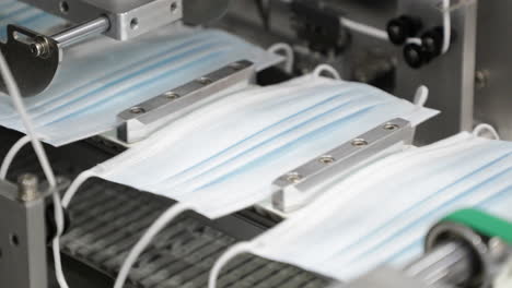 face mask with ear loops at production line in modern factory for air filtration - protection in coronavirus - close up shot