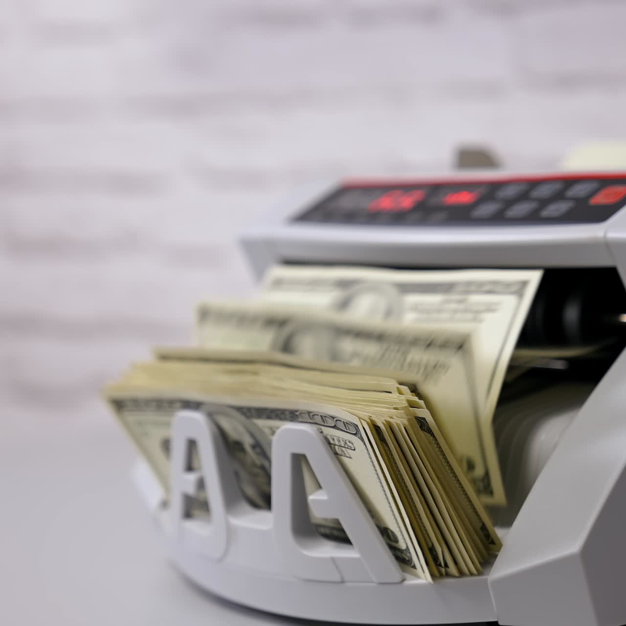 Attrezzatura bancaria automatica per il calcolo di banconote. Contabanconote che conta banconote da un dollaro. Impiegata che preleva un fascio di cento dollari USA dalla macchina automatica. Vista laterale.
