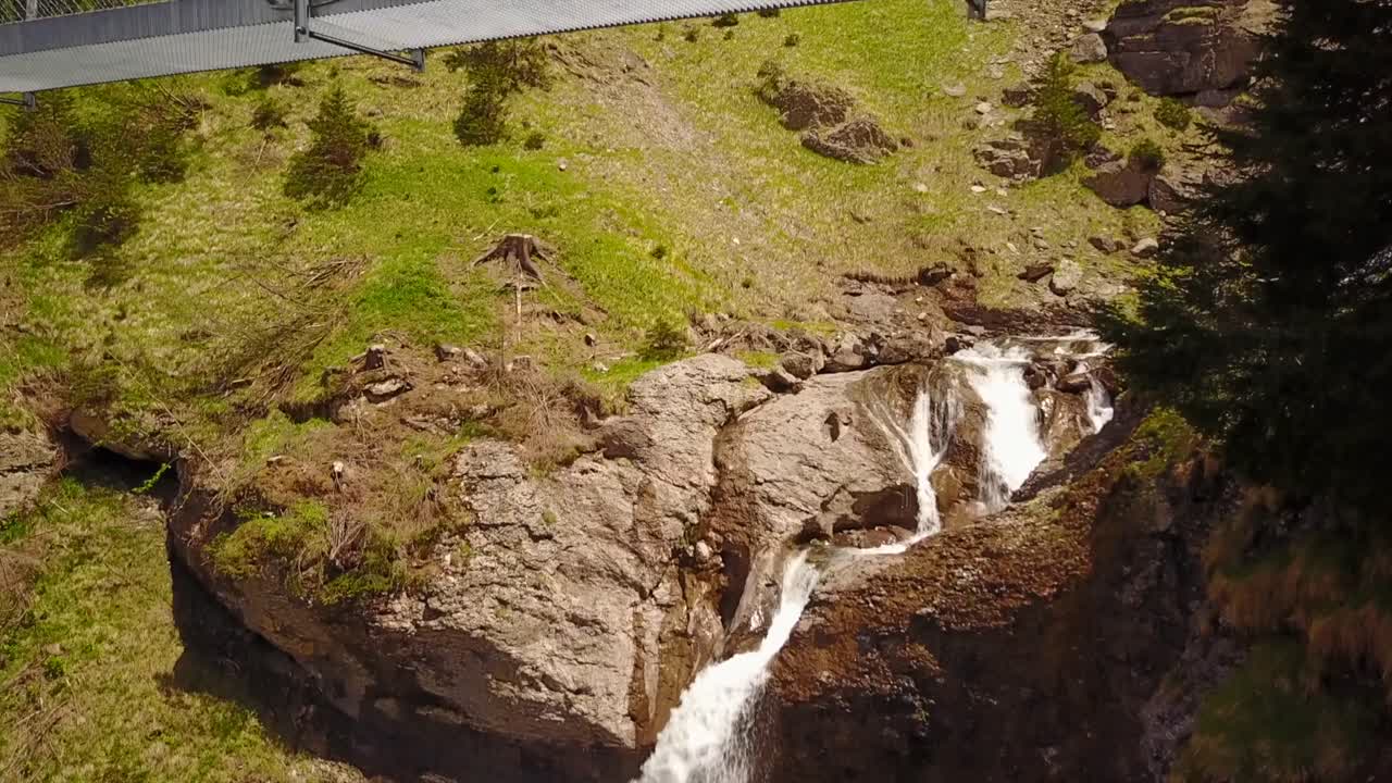 vista de una cascada seguida de una vista de un puente que cruza el río en los alpes suizos