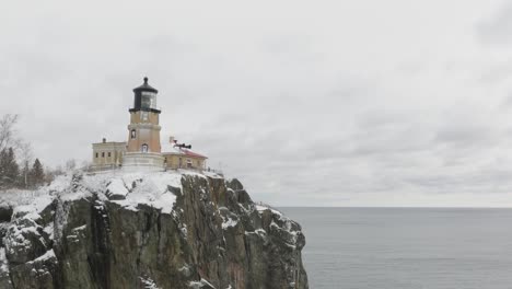 rocky cliff with lighthouse at split rock state park by the lake in winter in minnesota, usa. - aerial shot