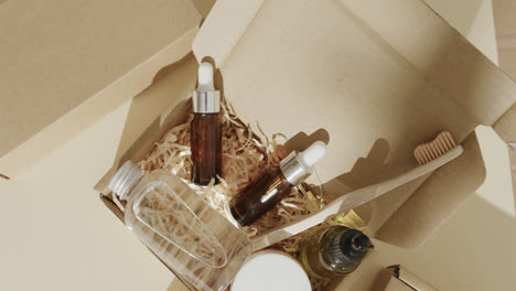 close up of cardboard boxes with glass bottles, cream tub and toothbrush on beige background