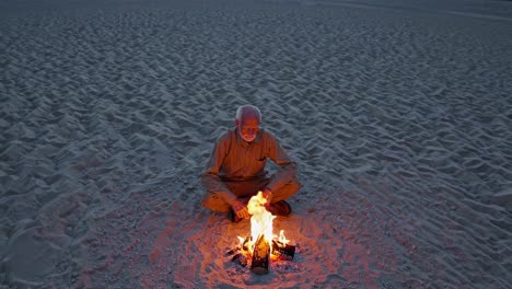 hombre anciano sentado junto a una fogata en el desierto
