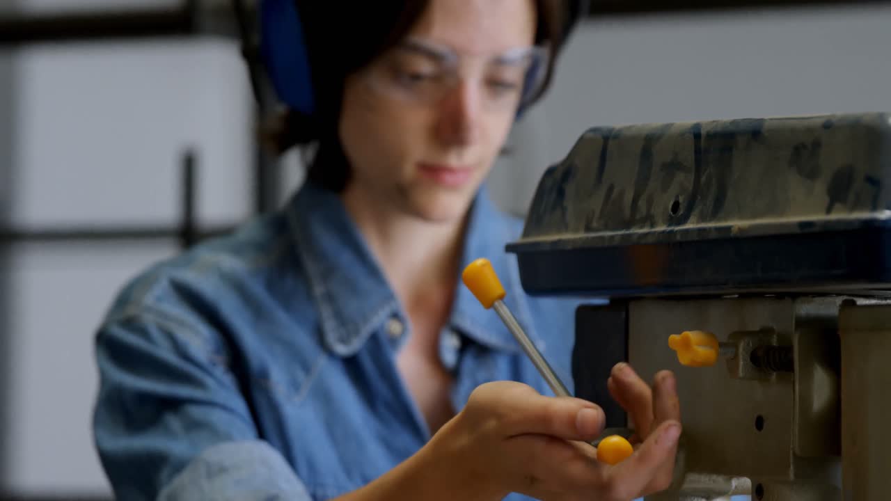 Female welder using drill press machine in workshop 4k