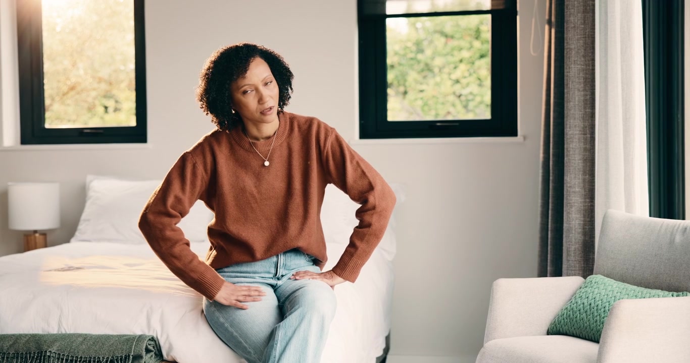 Woman Sitting on Bed Using Smartphone and Looking Away