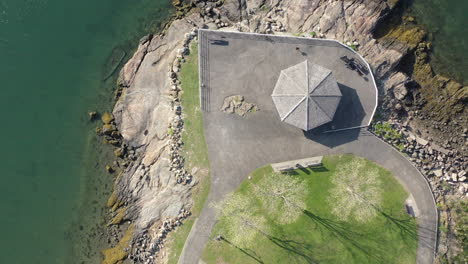 a top down view of a paved platform on top of rocks, on the water on a sunny day