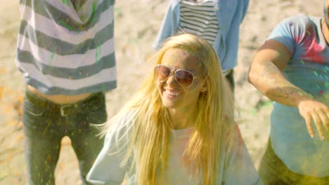 high angle shot of a blonde girl throwing colorful powder in the crowd amidst hindu holi festival celebrations. they have enormous fun on this sunny day.