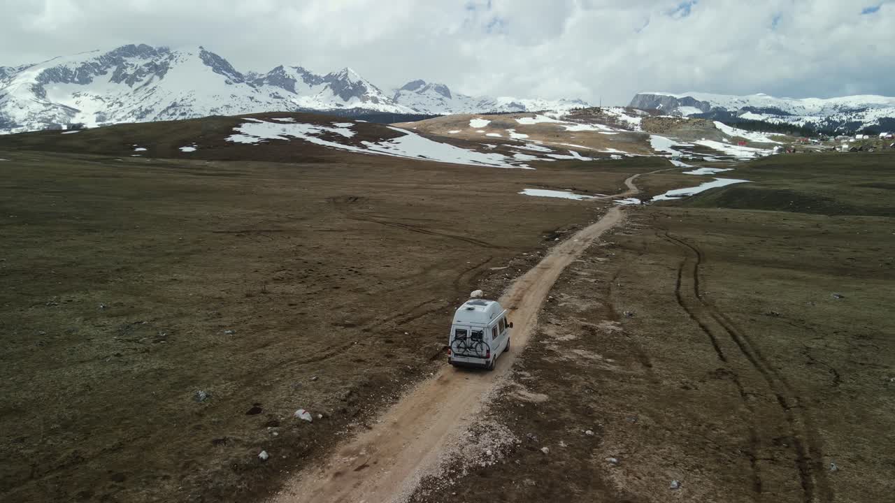 Ripresa aerea che segue lentamente un camper su una strada sterrata in montagna, Montenegro