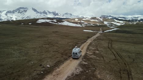 aerial slowly follows camper van on dirt road in mountains, montenegro