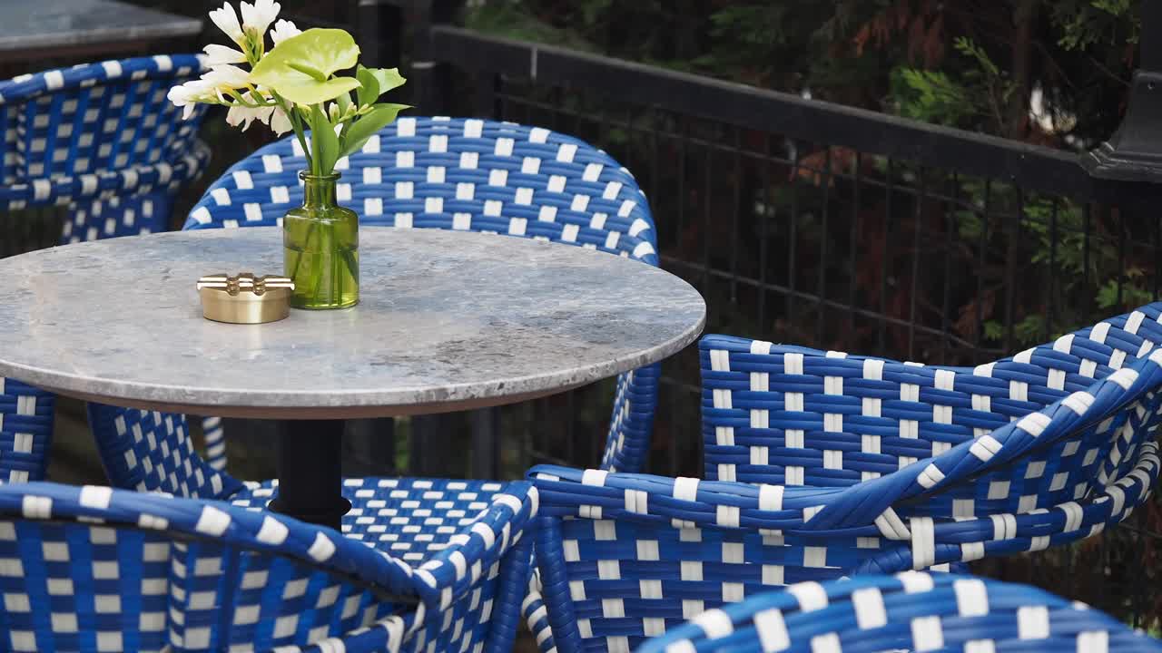Area salotto di un bar all'aperto con fiori e posacenere