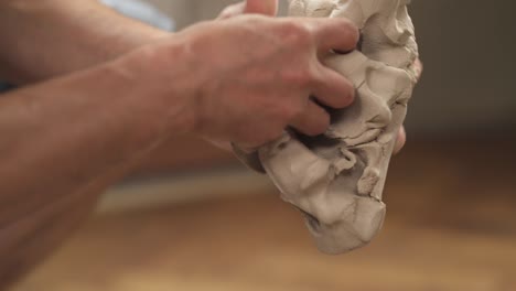 a close-up of a professional sculptors hands kneading clay for creating ceramic product in his workshop. isolated, blurred background