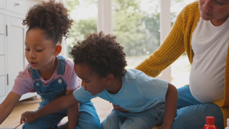 pregnant mother with children making welcome home banner for army father