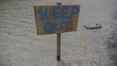 wooden keep out sign on a lake in slow motion