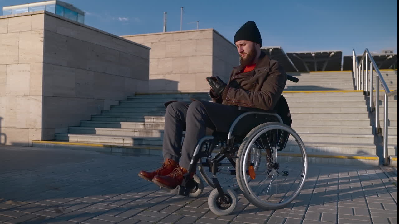 hombre en silla de ruedas usando un teléfono inteligente