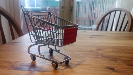 mini carrito de compras vacío concepto de entrega a domicilio en línea en la mesa de la cocina orbita a la derecha