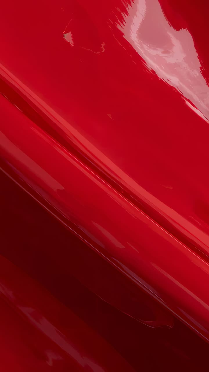 Video verticale: spostamento della camera che rivela un pannello curvo rosso lucido in studio, mostrando la giuntura e la lucentezza
