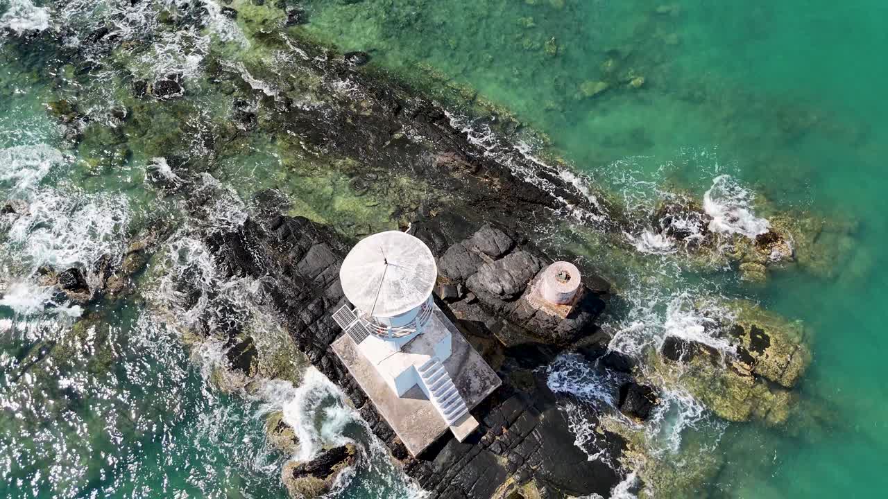 las imágenes de drones capturan un faro en costas rocosas con olas turquesas, mostrando perspectivas aéreas dinámicas y paisajes costeros vibrantes