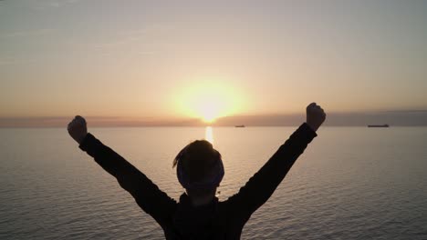 a young girl show victory sign on the top of the hill against the stunning view and sun